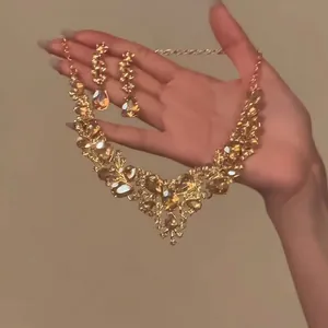 Nahaufnahme eines luxuriösen goldfarbenen Halsketten- und Ohrring-Sets mit Strasssteinen.