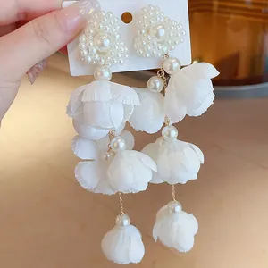 Close-up of elegant forest-style white fabric flower earrings with pearl clusters