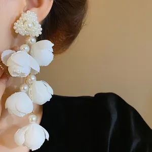 Detailed view of elegant forest style earrings with white fabric flowers and pearls