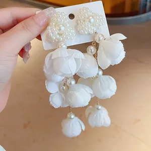 Detailed close-up of Mori-style white flower earrings with elegant pearl accents