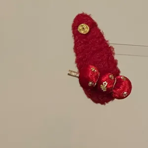 Detailed close-up of a red flocked hair clip with candied hawthorn and gold coin decor