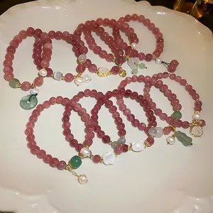 Set of pink strawberry quartz bracelets with pearls and charms on white ceramic plate