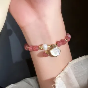 Elegant strawberry quartz bead bracelet featuring shell charm and pearl on lady's wrist