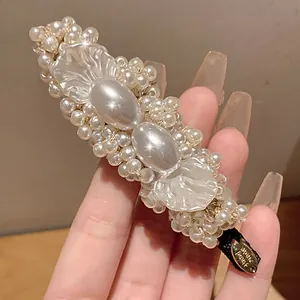 Detailed macro view of elegant pearl hair clip with handmade tag and petal accents