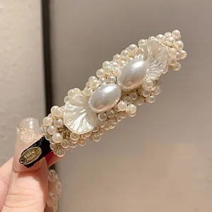 Detailed macro shot of vintage pearl petal hair clip with handcrafted metal tag