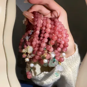 Close-up of elegant strawberry quartz and pearl beaded bracelets with shell charms held in hand
