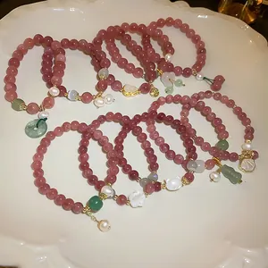 Detailed view of pink strawberry quartz beaded bracelets with mixed charms on a white plate