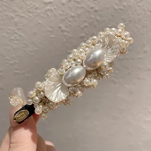Detail of a vintage hair clip with white pearls and delicate shell petal decorations.