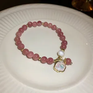 Close-up of strawberry quartz beaded bracelet with shell charm and white pearl