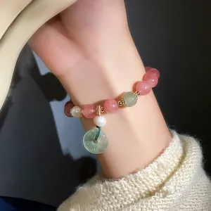 Close-up of strawberry quartz and pearl beaded bracelet with jade donut charm on wrist