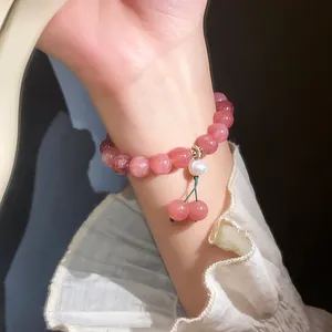 Detailed macro view of a pink strawberry crystal bead bracelet with a pearl cherry charm