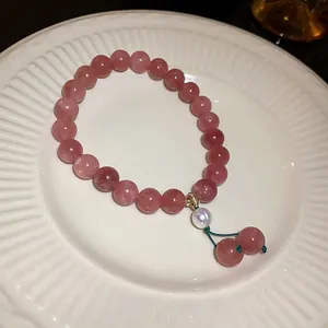 Detailed macro shot of pink strawberry quartz bracelet with a pearl accent on white plate