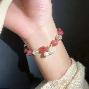Detailed macro shot of a delicate strawberry quartz and pearl beaded bracelet on a wrist