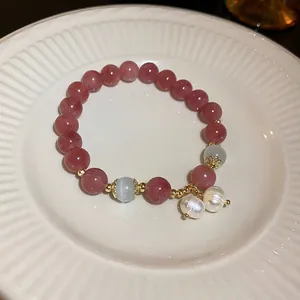 Close-up of pink strawberry quartz beads and white pearl charms on a ceramic plate