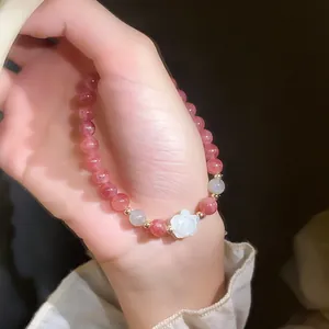 Detailed view of a pink strawberry quartz beaded bracelet with a white shell rose charm