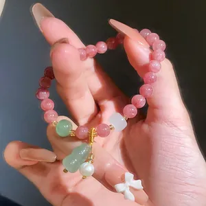 Close-up detail of strawberry quartz beaded bracelet with green gourd and pearl charms