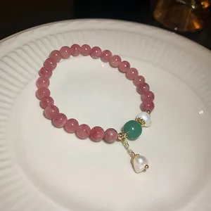 Detailed macro view of pink strawberry quartz bracelet featuring a delicate pearl pendant