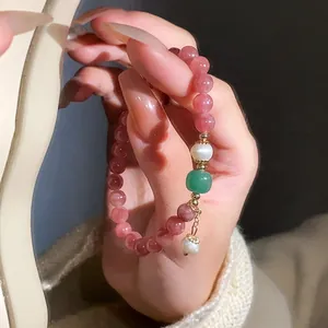 Close-up detail view of a pink strawberry quartz and white pearl beaded bracelet on hand