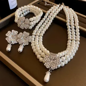 Detailansicht eines mehrlagigen Perlen-Schmucksets mit kristallbesetzten Blumen