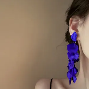 Close-up of vibrant blue rose petal tassel earrings on model for an elegant look