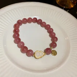 Close-up of pink crystal bead bracelet with shell gourd charm and golden Fu tag