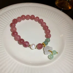 Close-up detail of strawberry quartz beaded bracelet with pearl and lily flower charm.