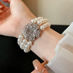 Nahaufnahme eines mehrlagigen Perlenarmbands mit glitzerndem Diamantblumen-Anhänger
