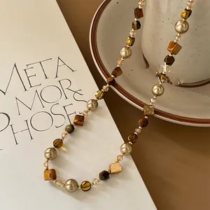Macro view of irregular tiger eye stone and pearl beaded necklace with vintage charm