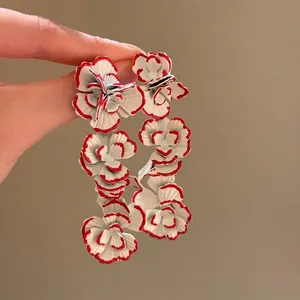 Detail of oversized retro floral earrings with white and red edged petals