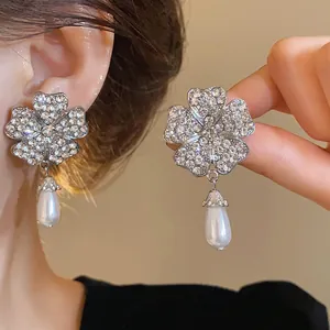 Nahaufnahme von eleganten Blumenohrringen mit glitzernden Strasssteinen und Perlen