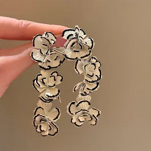 Detailed view of vintage-style white flower earrings with black hand-painted edges.