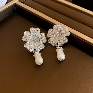 Detailansicht von Blumenohrringen mit Strasssteinen und eleganten Tropfenperlen
