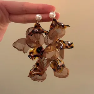 Close-up of vintage oversized flower earrings with tortoise pattern petals and pearls.