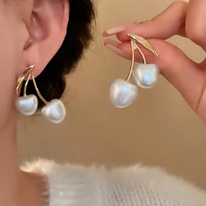 Minimalist French style cherry drop earrings featuring white pearls and gold metal stems