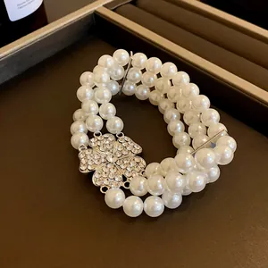 Detailansicht einer mehrreihigen Perlenkette mit einem glitzernden Blumenanhänger aus Strass