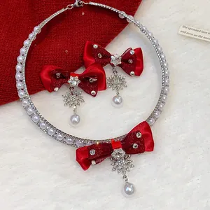 Detail view of elegant red bow jewelry set featuring crystal snowflake and pearl charms