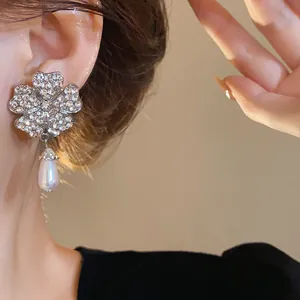 Nahaufnahme von französischen Luxus-Blumenohrringen mit Strass und Perlendetail