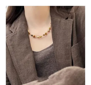 Detail view of tiger eye and pearl beaded choker necklace on model in Maillard style