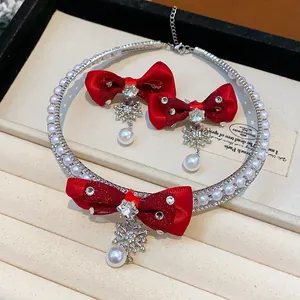 Close-up of a festive jewelry set featuring red bows, snowflakes, and pearls on a display tray.