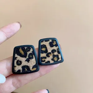 Primer plano de pendientes de leopardo trapezoidales con detalle de piel sintética