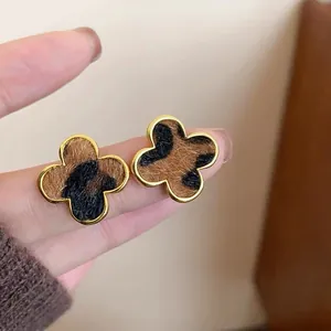 Detalle de pendientes de trébol vintage con estampado de leopardo y borde dorado