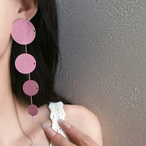 Detailed view of elegant pink textured round disc tassel earrings worn by a model
