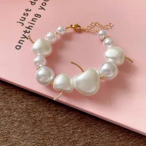 Close-up of white pearl bracelet with gold-tone cherry stem accents and lobster clasp.