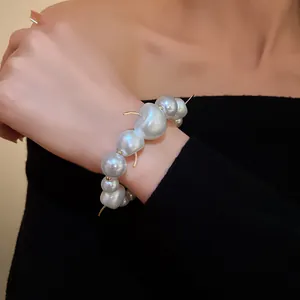Detail shot of baroque pearl bracelet with gold accents on wrist with black top