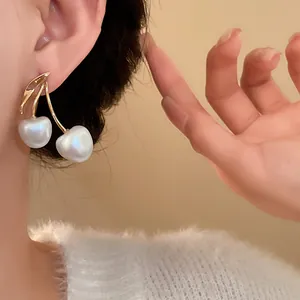 Close-up of elegant cherry-shaped earrings with large white pearls and gold stems