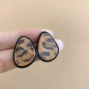 Primer plano detallado de pendientes de botón vintage con estampado de leopardo.