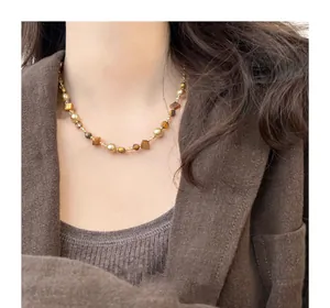 Detailed view of the irregular tiger eye and pearl beaded choker necklace worn by a model