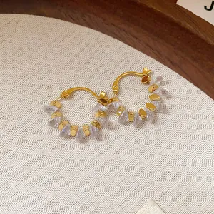 Dettaglio ravvicinato di orecchini a cerchio placcati oro 18k con cristalli trasparenti
