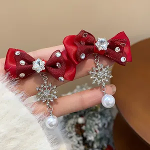 Detailed view of elegant red ribbon bow earrings with crystal snowflakes and pearls