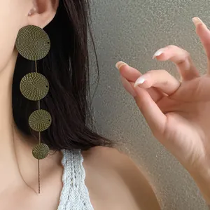 Close-up of vintage olive green disc tassel earrings showing exquisite textured details
